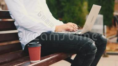作物。 商人，穿着商业风格，坐在公园里的户外，在笔记本电脑上打字